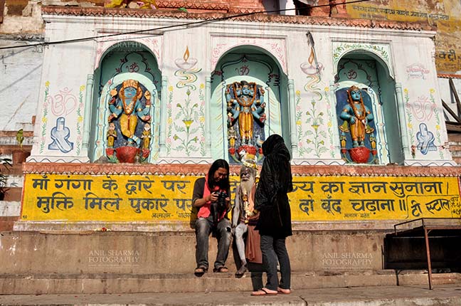 Travel- Varanasi the city of light (India) - A photographer showing picture to Naga Sadhu at Ghats at Varanasi, Uttar Pradesh, India. by Anil