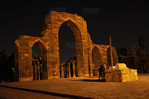 Monuments- Qutab Minar in Night, New Delhi, India. - The Beauty of arches of  Iltutmish screen and some tourists standing near the  iron pillar in night at Qutub Minar Complex, Mehrauli , New Delhi, India. by Anil