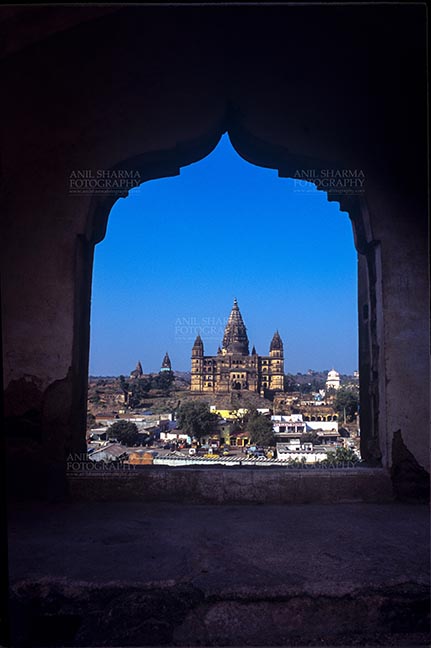 Monuments- Palaces and Temples of Orchha - Orchha, Madhya Pradesh, India- May 14, 2008: View from a carved window of Jahangir Mahal, Chaturbhuj temple is seen in the distance, Orchha, Madhya Pradesh, India. by Anil
