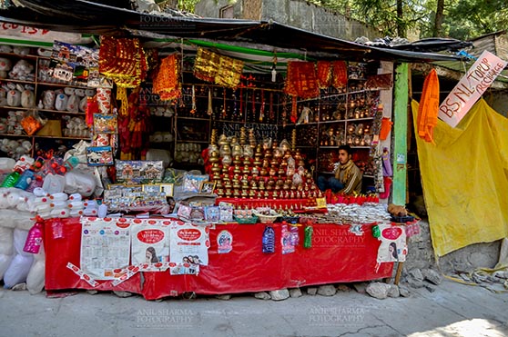Travel- Gangotri (Uttarakhand) - Gangotri, Uttarakhand, India- May 13, 2015: A shopkeepers selling plastic bottles and devotional objects, for religious ceremonies at Gangotri, Uttarkashi, Uttarakhand, India. by Anil