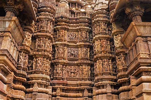 Monuments-  Khajuraho Temples (Madhya Pradesh) - Close-up of the patterned panels with carvings depicting erotic scenes on the Kandariya Mahadev temple at Khajuraho. by Anil