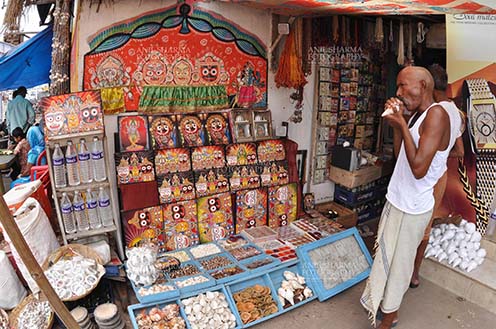 Festivals- Jagannath Rath Yatra (Odisha) - Memento of Lord Jagannath, Balbhadra and Subhadra on display and an old customer at the shop near Lord Jagannath Temple at Puri, Odisha, India. by Anil
