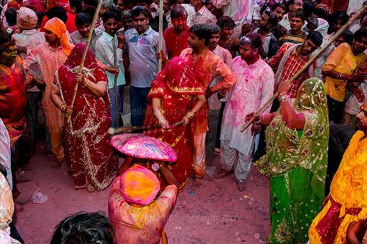A man from Nandgaon protecting himself from womens of Barsana hitting on his shield with their sticks during Lathmaar Holi at Barsana.