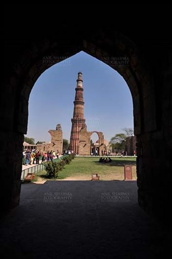 Qutub Minar the tallest brick minaret in the world seen through arch at Qutub Minar Complex, New Delhi, India.