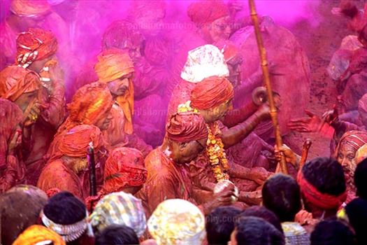 People daubed in colored water, head covered singing a hymn during Lathmaar Holi celebrations at Barsana, Mathura, India.