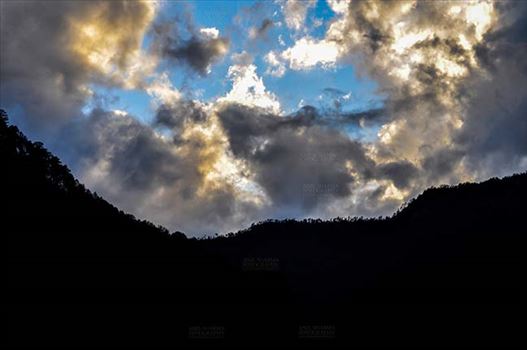 Clouds over Uttarkashi Hills, Uttarakhand, India-  June 17, 2013: Blue sky in the evening with light yellow and grey clouds over the hills of Uttarkashi, Uttarakhand, India.